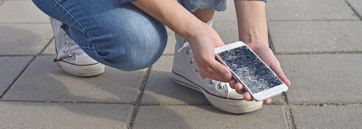 Persoon die een kapotte smartphone vasthoudt met een gebarsten scherm